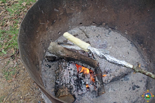 roll dough wrapped around a stick roasting over a campfire