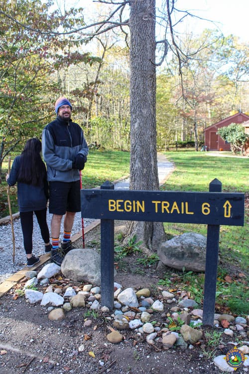 man next to begin trail 6 sign 