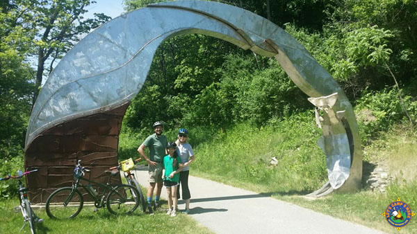 family next to a sculpture on a bike trail