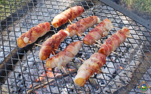 bacon mozzarella cheese sticks on a grill while camping