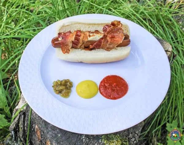 bacon wrapped hot dog with cheese and condiments