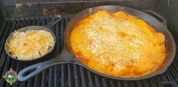 2 cast iron skillets of nachos on a grill