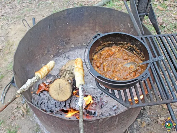 stew and rolls being cooked over a campfire