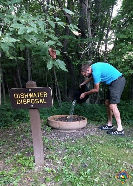 man pouring out dish water at a campground
