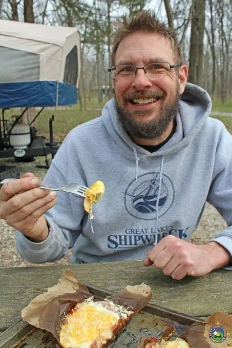 smiling man enjoying a camping breakfast