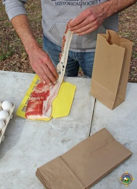 man pulling a piece off a package of bacon