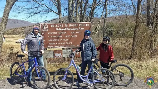 family posing with bicycles in front of the Mount Rogers sign