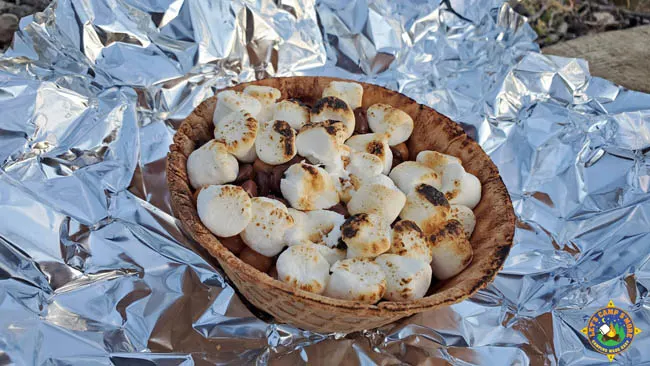 a waffle bowl filled with s'more fixings laying on a piece of foil