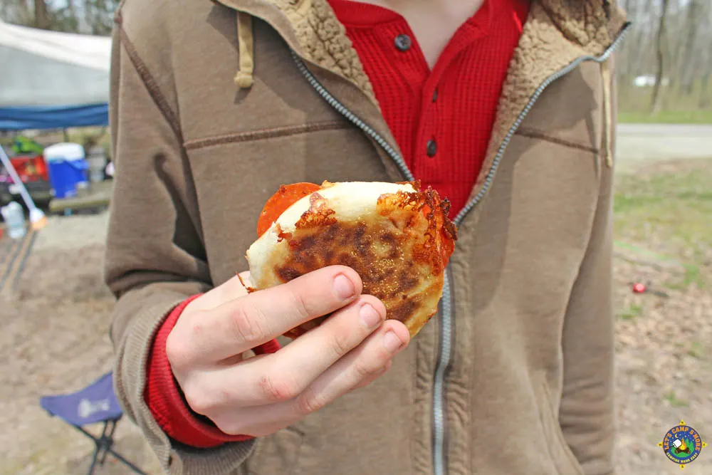person holding a pizza sandwich while camping