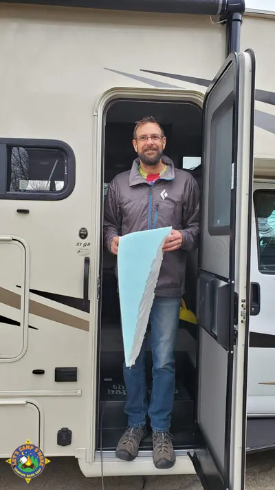 man standing the doorway of a motorhome holding a piece of foam
