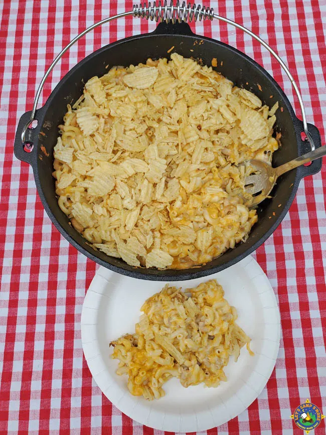 Dutch Oven with Macaroni and Cheese and a white plate with a serving on it on top of a red checkered tablecloth