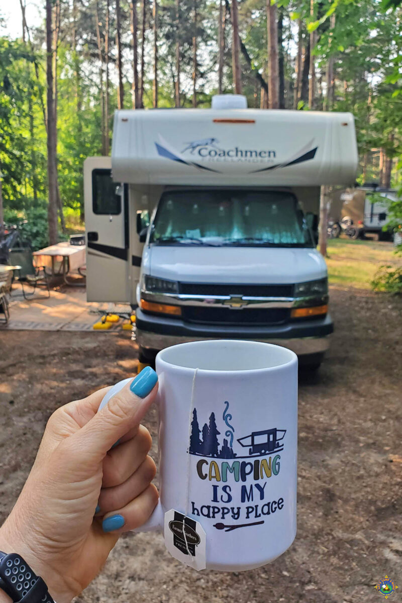 Camping is my Happy Place mug being held by a woman in front of a motorhome at site 108 at Holland State Park campground