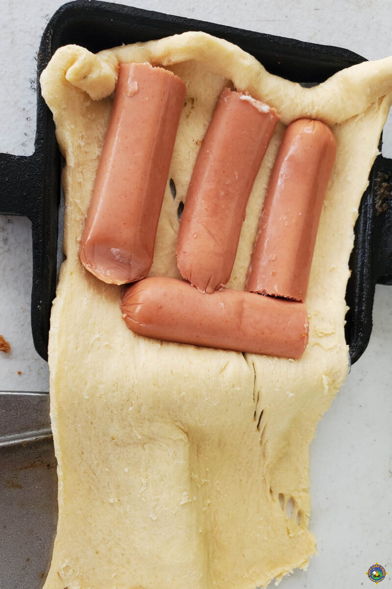 Cut up hot dogs in dough in a pie iron