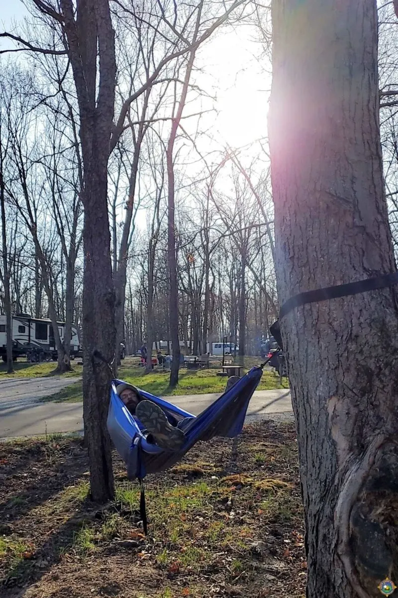 man sleeping in a hammock at a campground