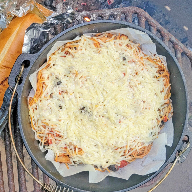 Baked Spaghetti in a lined Dutch Oven with melted cheese on top
