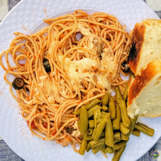 a plate with a serving of campfire spaghetti with a side of green beans and bread