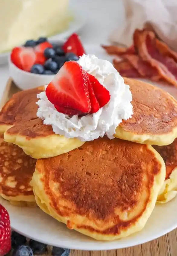 pancakes with berries and cream with a side of bacon